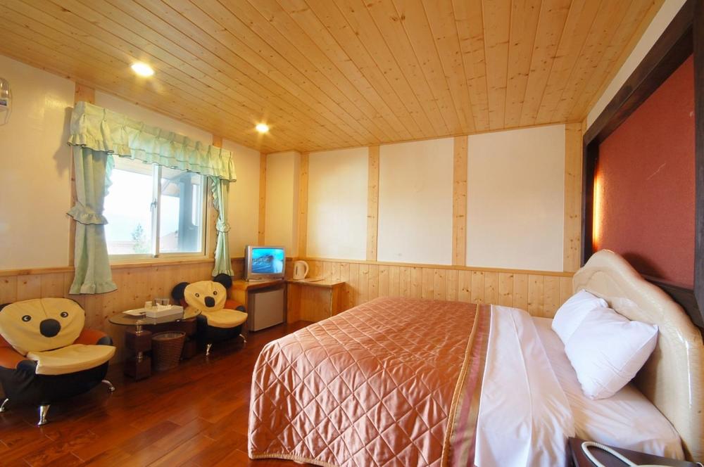 a bedroom with a bed and a tv in it at Sea of Clouds Vacation Villa in Ren&#39;ai