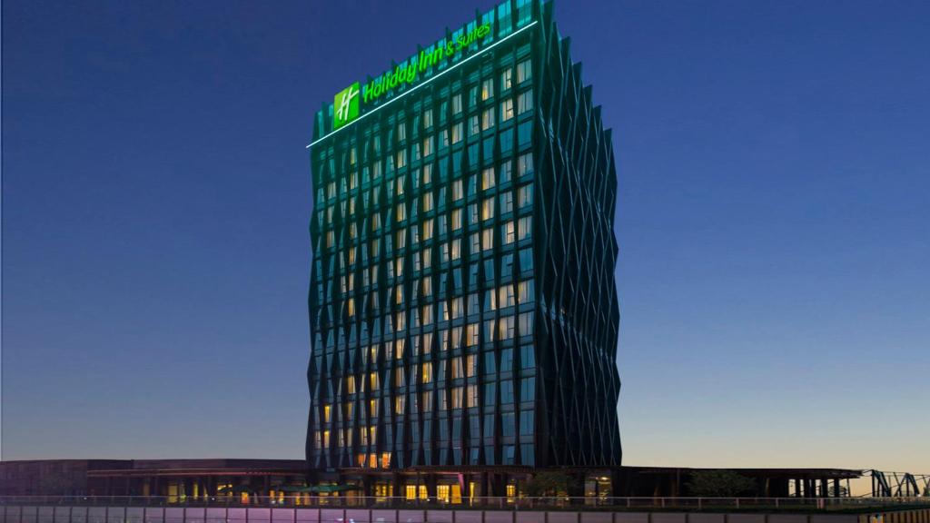 JiangningにあるHoliday Inn Nanjing Qinhuai South Suites, an IHG Hotelの緑の看板が立つ高層ビル