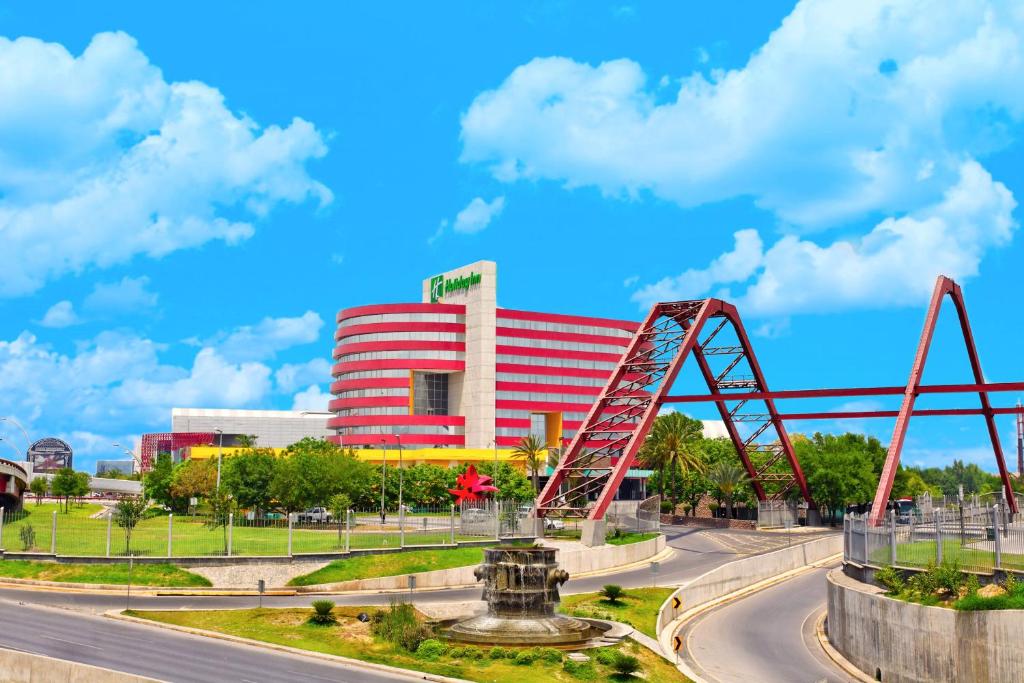 Holiday Inn Monterrey-Parque Fundidora, an IHG Hotel في مونتيري: طريق امام مبنى فيه جسر