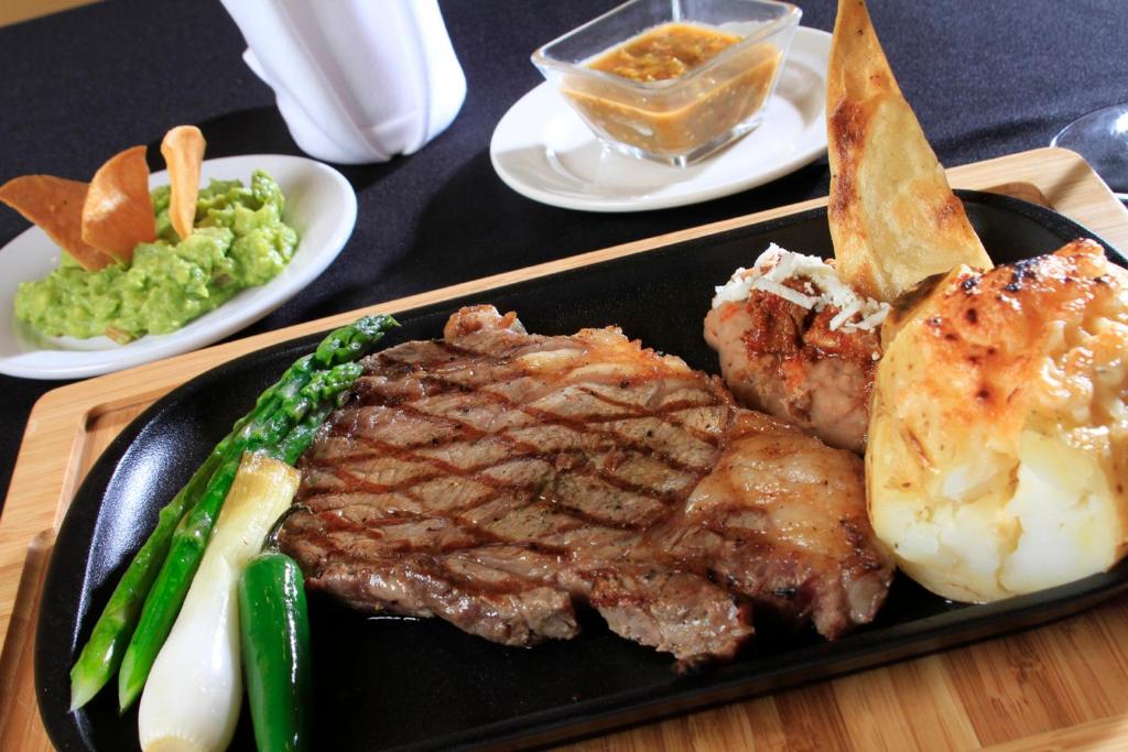 a black plate with steak and vegetables on a table at Holiday Inn Monterrey-Parque Fundidora by IHG in Monterrey