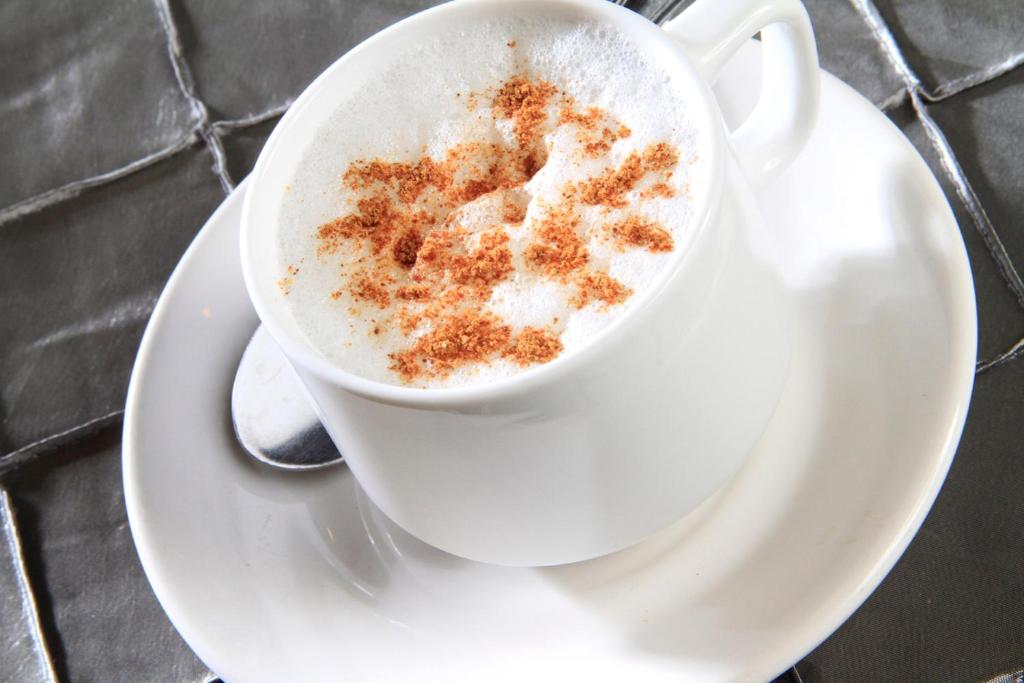 a cup of coffee sitting on a plate at Holiday Inn Monterrey-Parque Fundidora by IHG in Monterrey