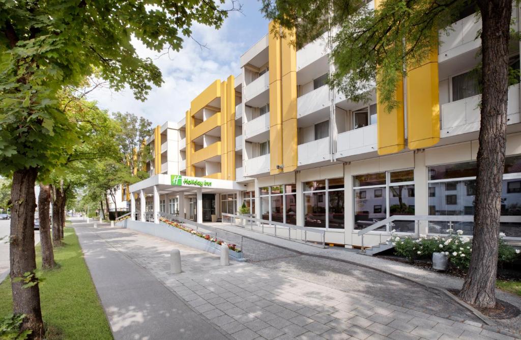 un edificio de apartamentos con fachada de color amarillo y blanco en Holiday Inn Munich - South, an IHG Hotel, en Múnich