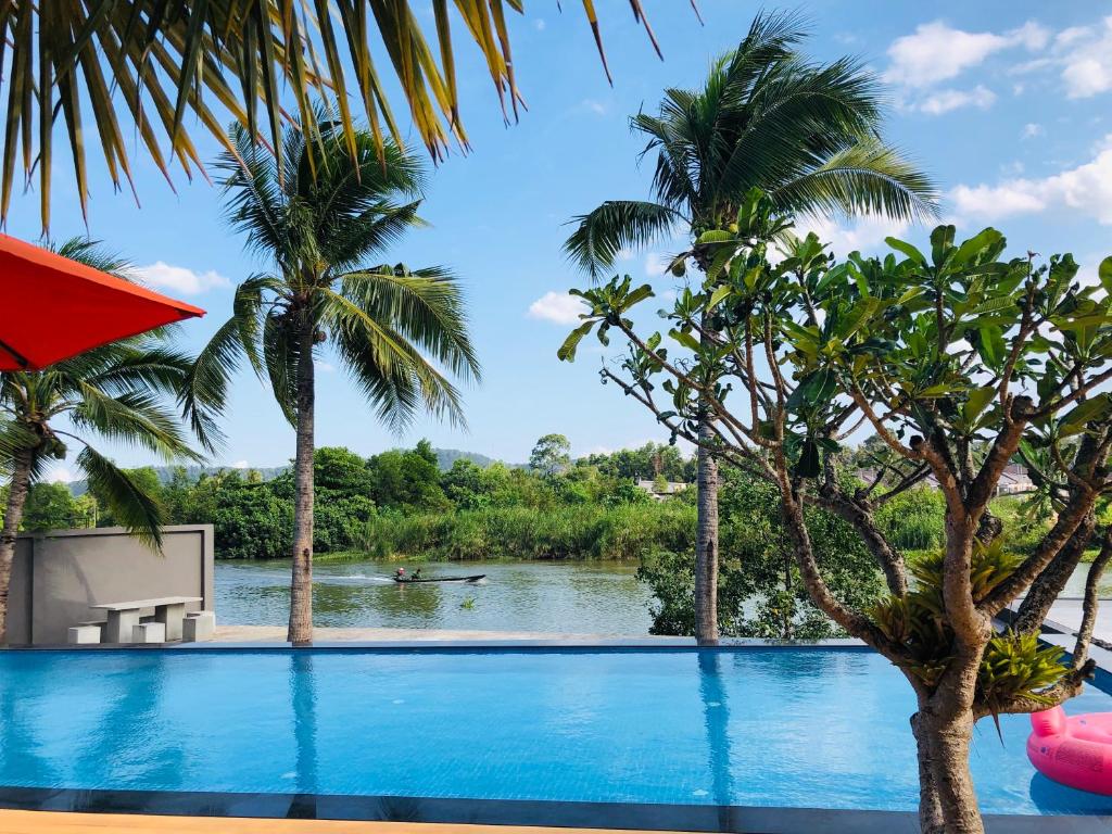una piscina con palmeras y un río en AreNice Boutique Hotel en Surat Thani