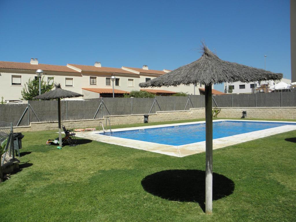 una piscina con sombrilla de paja y una piscina en Apartamento en Jerez de la Frontera 2, en Jerez de la Frontera