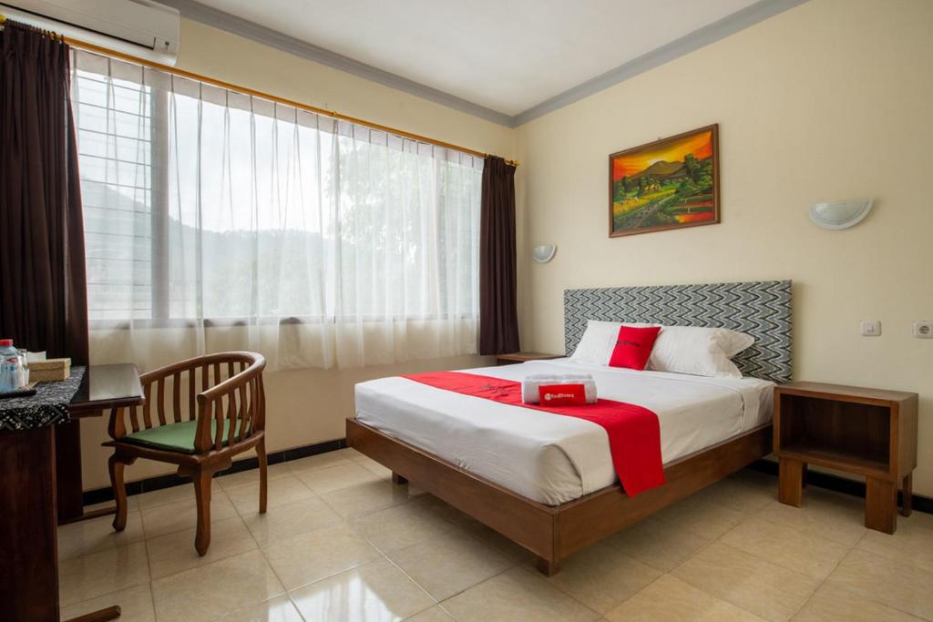 Un dormitorio con una cama y un escritorio y una ventana. en RedDoorz Plus near Balai Kota Batu 2, en Malang