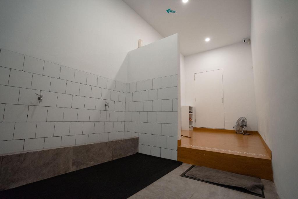 an empty bathroom with white tiled walls and a bench at Bobopod Kota Tua, Jakarta in Jakarta