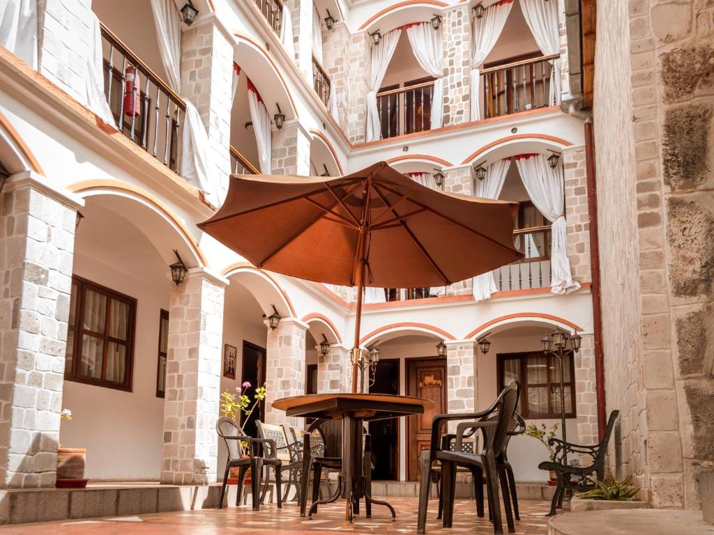 a table with an umbrella in the courtyard of a building at Latacunga Hostel in Latacunga