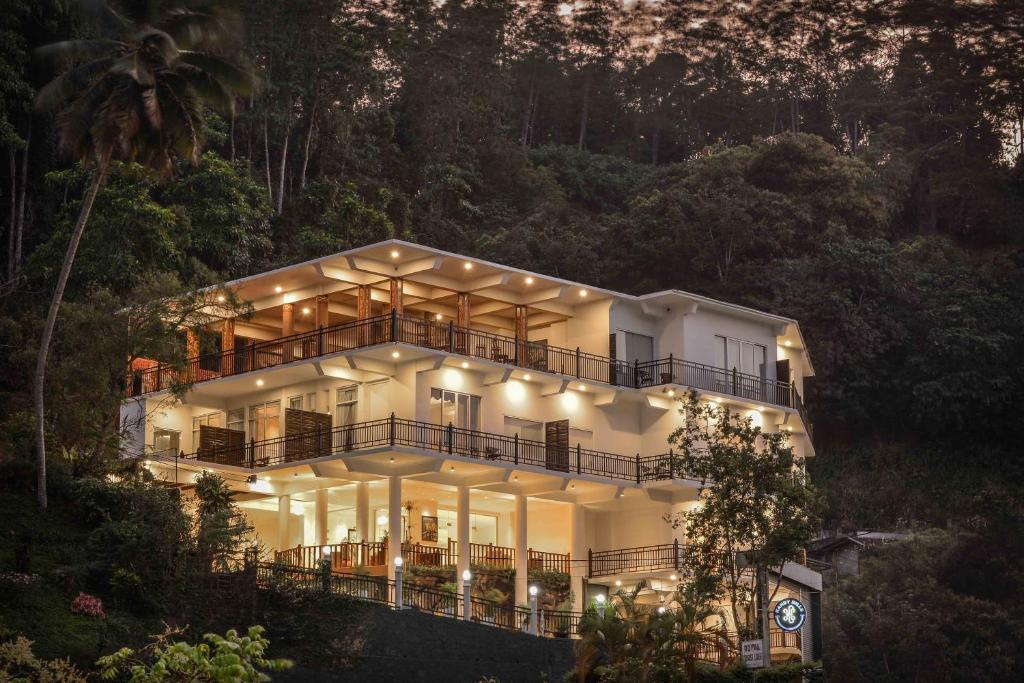 a large white house with lights in the forest at Kandy Hills in Kandy