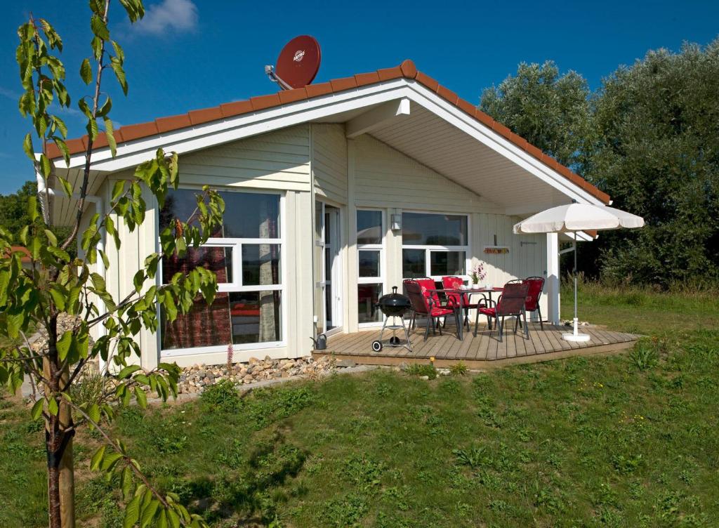 un cottage avec une table et des chaises sur une terrasse dans l'établissement Dänische Ferienhäuser am Salzhaff Haus Vogelparadies, à Poel