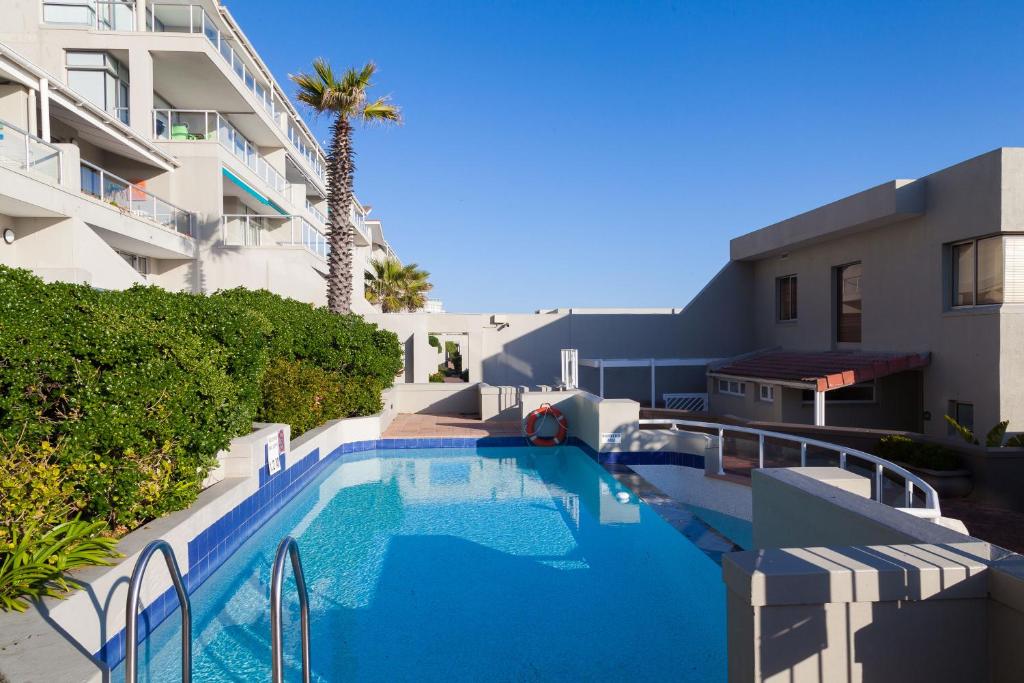 a large swimming pool next to a building at Dolphin Beach Hotel Self Catering Apartments in Bloubergstrand