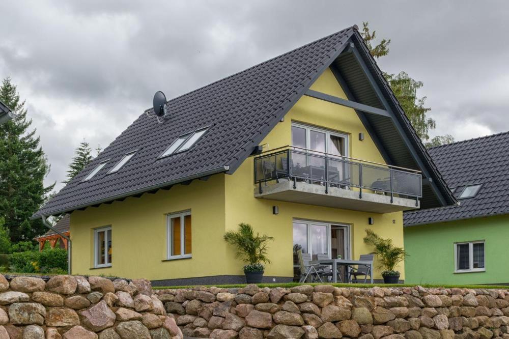 uma casa amarela e verde com um telhado preto em U12 EG - Charmante Ferienwohnung am See mit Kamin in Röbel an der Müritz em Marienfelde