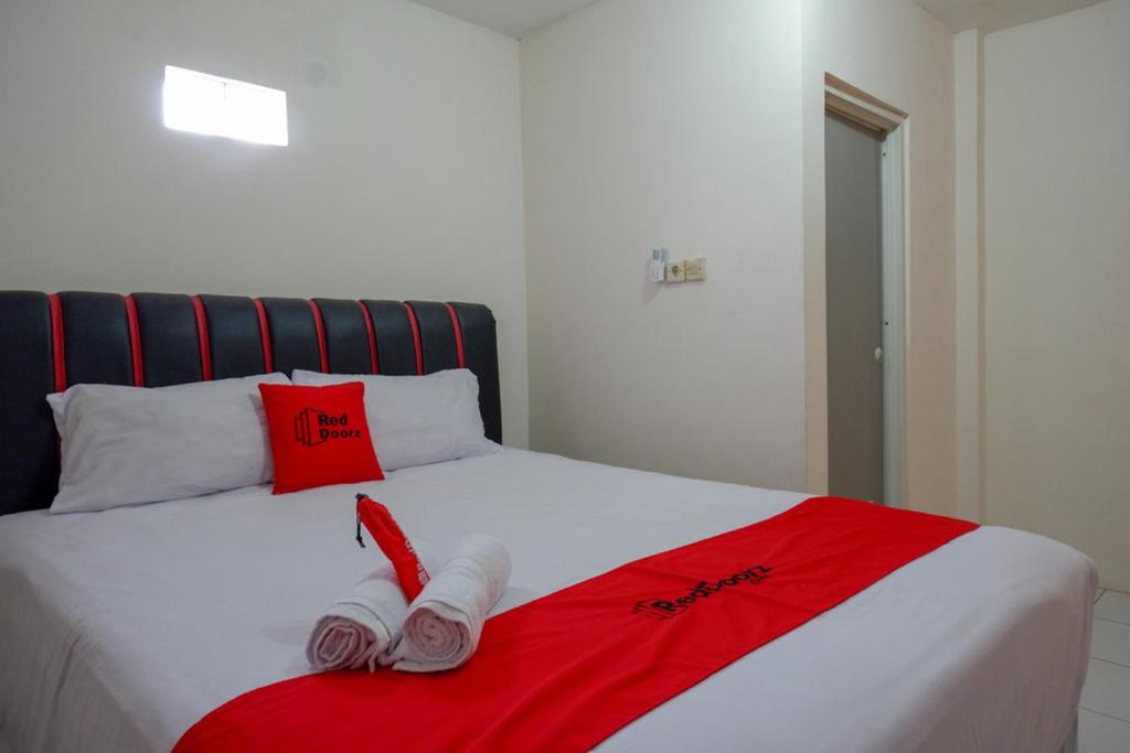 a bed with red and white towels on it at RedDoorz Syariah near GOR Satria 4 in Sumbang