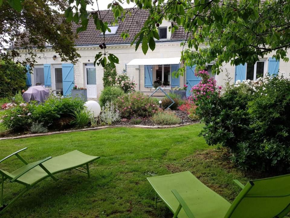 een tuin met twee groene stoelen en een huis bij AU GRÉ DE LALOIRE in Bréhémont