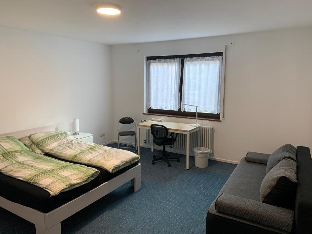 a bedroom with a bed and a desk and a couch at Big, cosy and central apartment in Karlsruhe