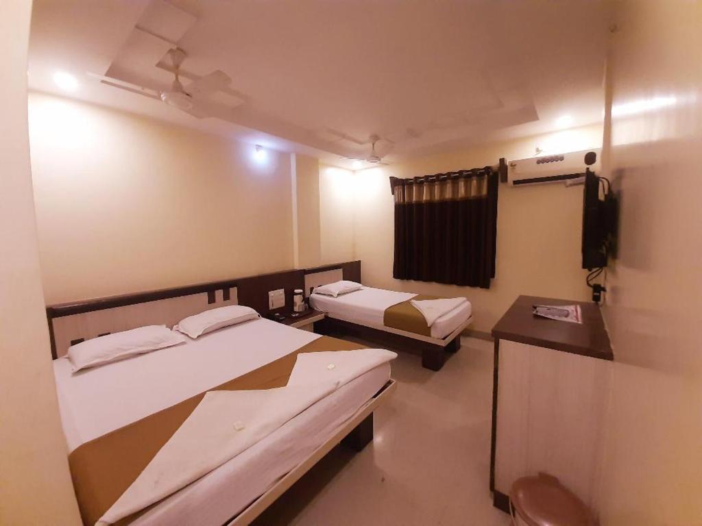 Habitación pequeña con 2 camas y TV. en Hotel Sai Balaji, en Shirdi