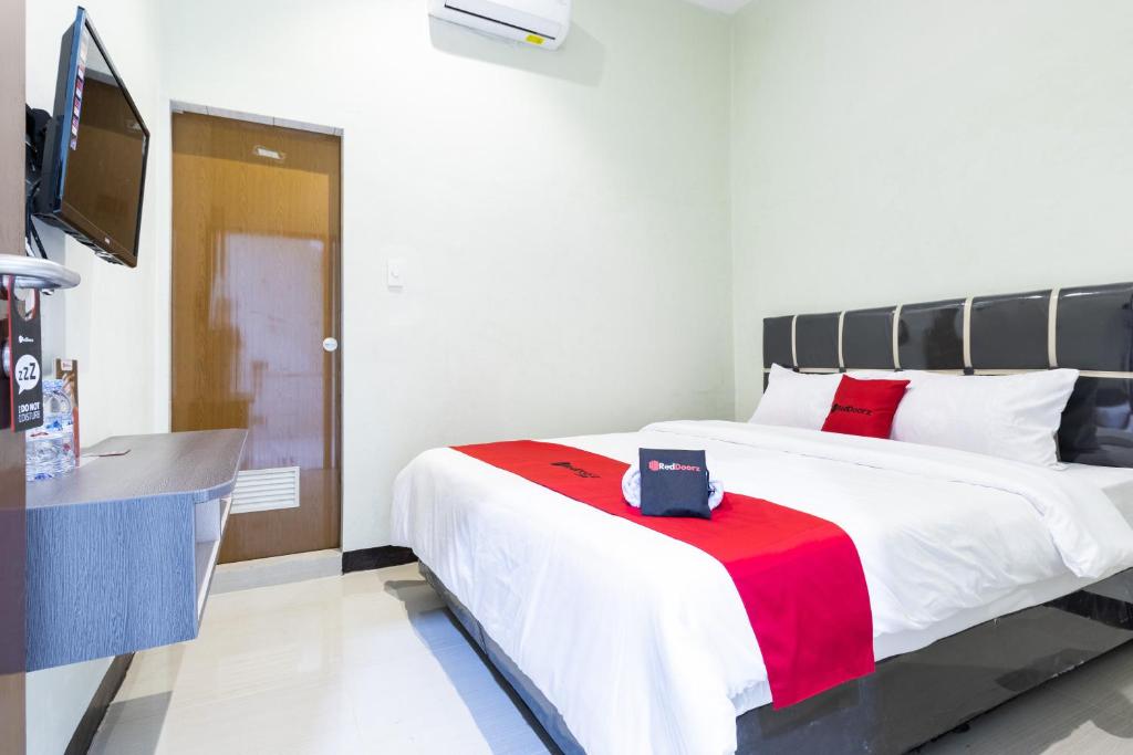 a bedroom with a large bed with a red blanket at RedDoorz near Medan Amplas in Delitua