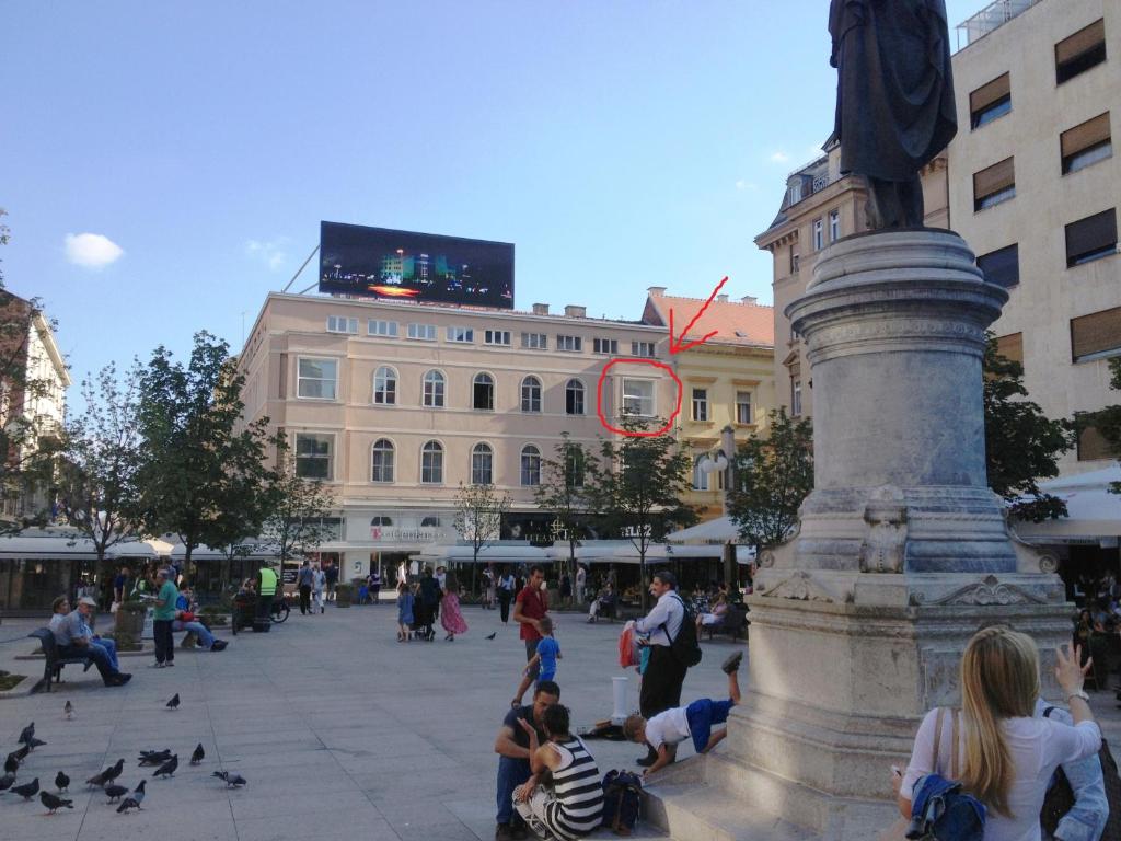 Un gruppo di persone sedute intorno a una fontana in una città di Apartment Exclusive View Cvjetni trg a Zagabria