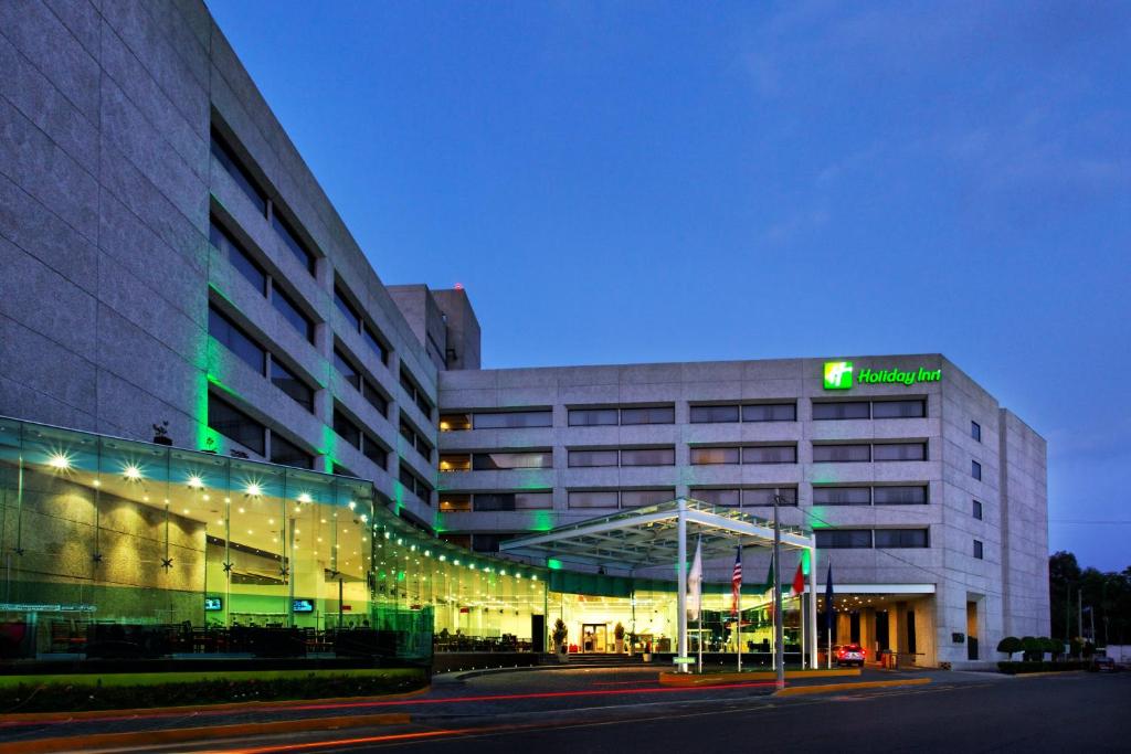 un grande edificio con un cartello verde di Holiday Inn Mexico City-Plaza Universidad, an IHG Hotel a Città del Messico