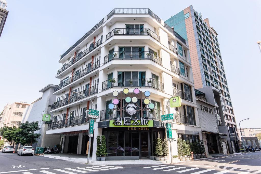 a tall white building with a sign on it at Tree House in Anping