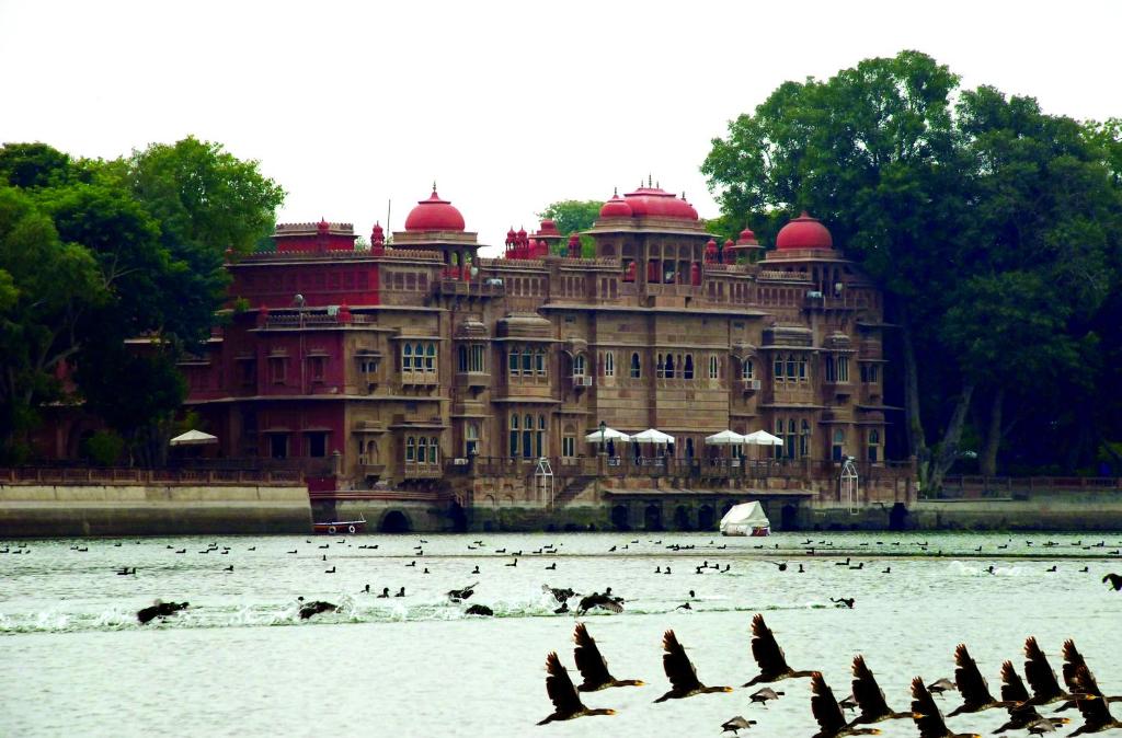 - un grand bâtiment avec des personnes au bord de l'eau dans l'établissement Gajner Palace-Heritage by HRH Group of Hotels, à Gajner