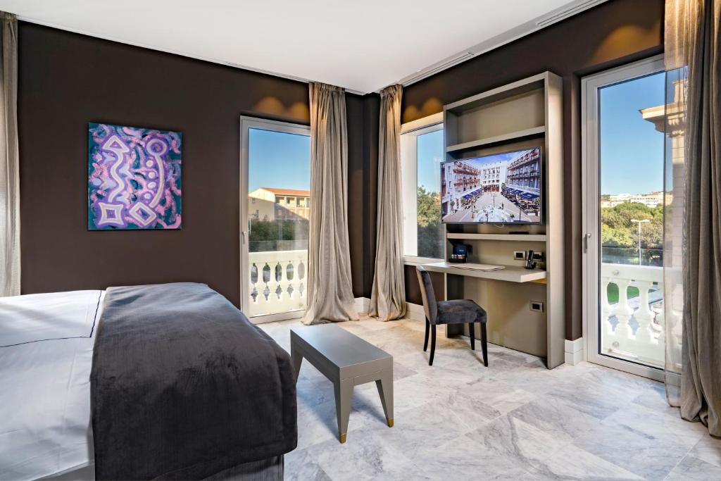 a bedroom with a bed and a desk and windows at Palazzo Doglio in Cagliari