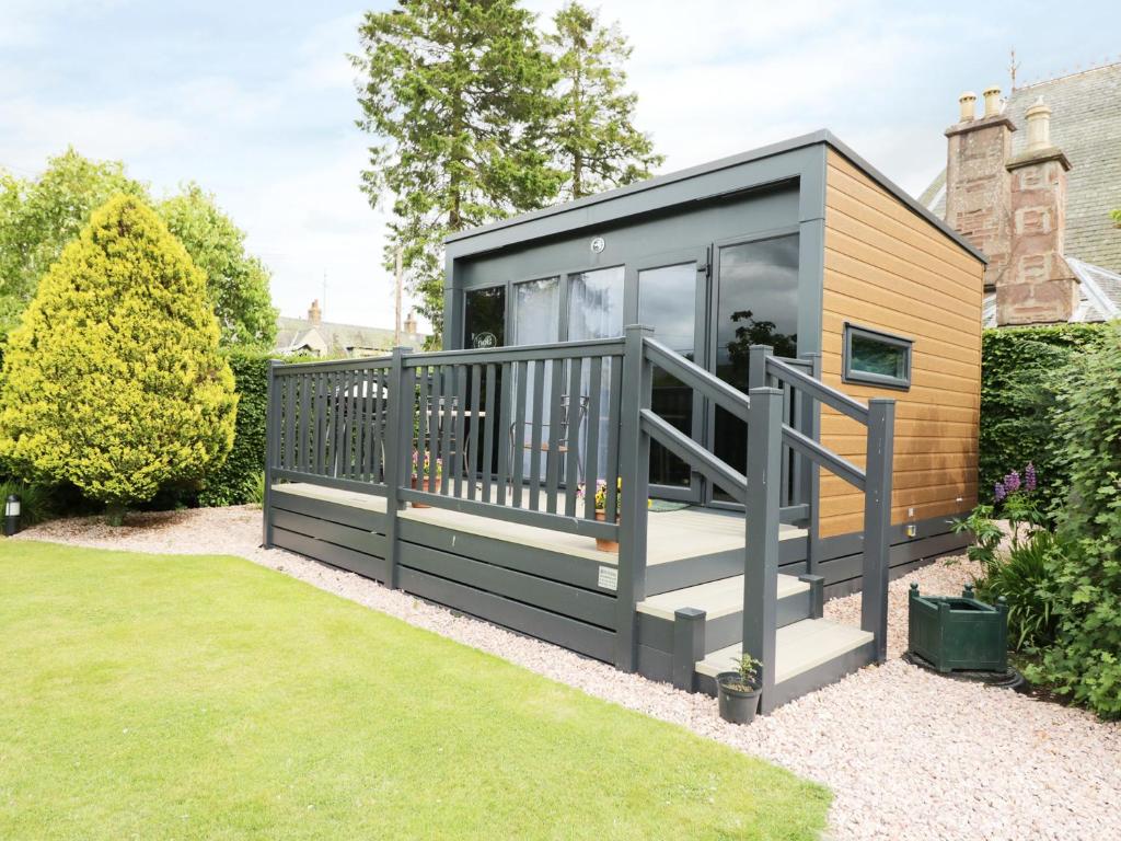 a tiny house with a deck in a garden at Cabin at the Tavern in Blairgowrie