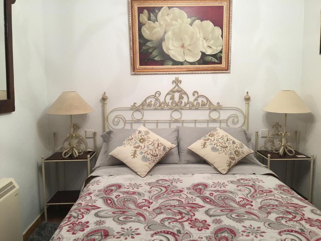 a bed with two lamps and a picture on the wall at Chalet El Descanso in Rades de Abajo