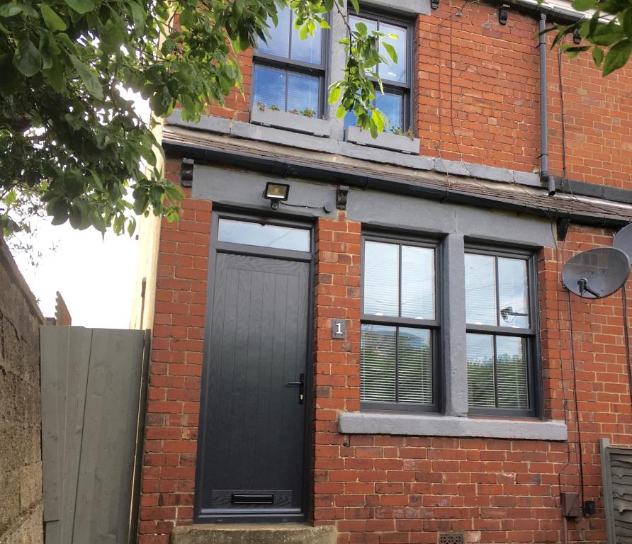 a brick house with a black door and windows at Number One in Wetherby