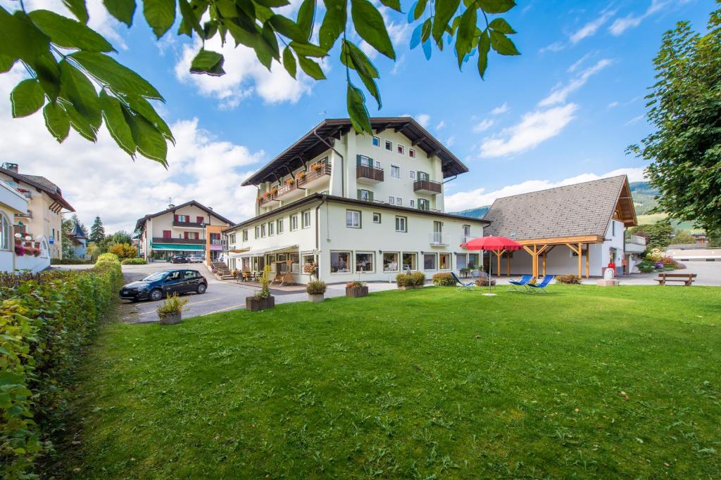 a large white building with a green lawn at Hotel Nocker in Dobbiaco