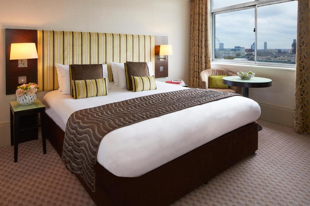 a large bed in a hotel room with a window at The Cavendish London in London
