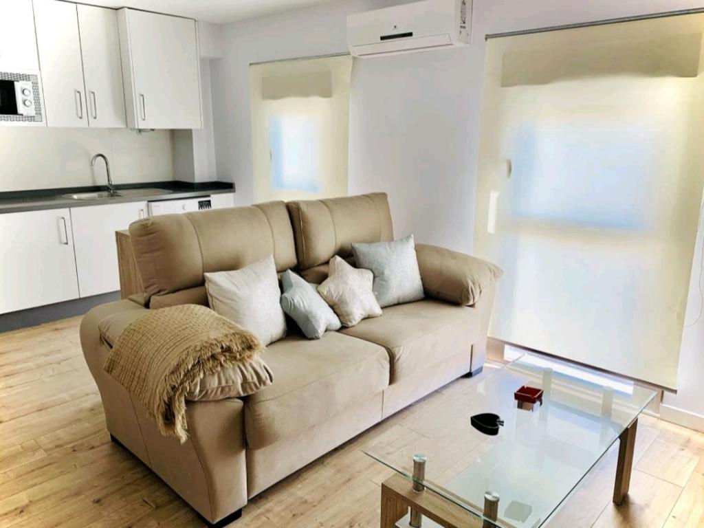 ein Wohnzimmer mit einem Sofa und einem Glastisch in der Unterkunft Alojamientos Vandelvira in Jaén