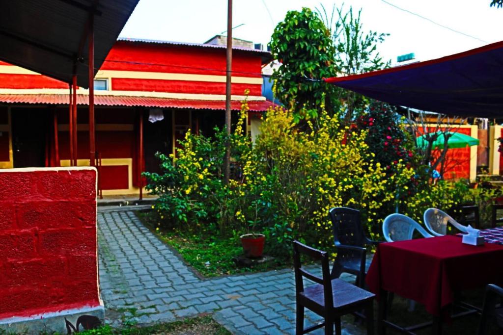 博卡拉的住宿－Gurkha Lodge，庭院配有桌椅和遮阳伞。