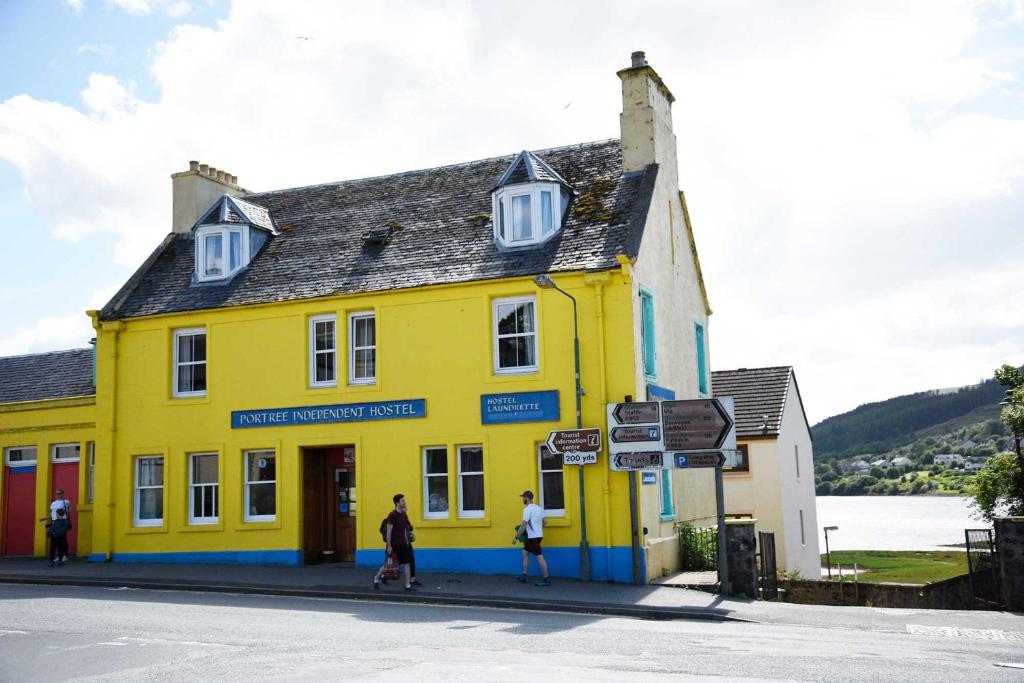 a yellow building with people walking in front of it at Portree Independent Hostel in Portree