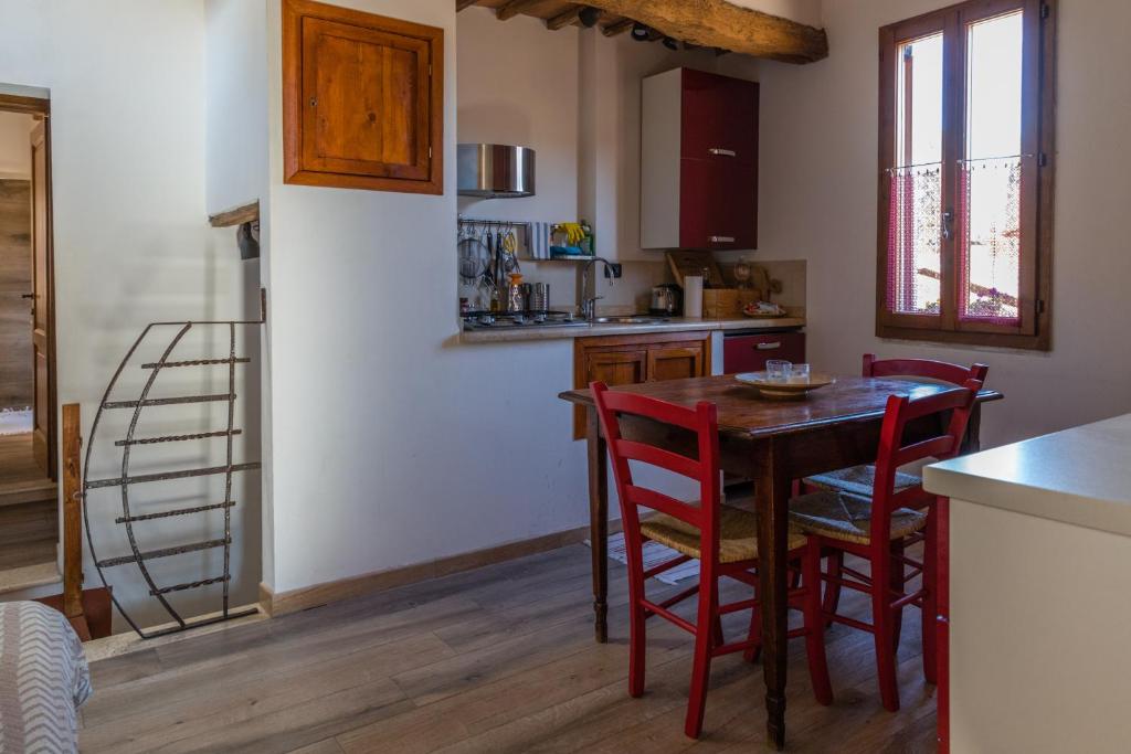 een keuken met een houten tafel en rode stoelen bij Appartamento Porta Pispini in Siena