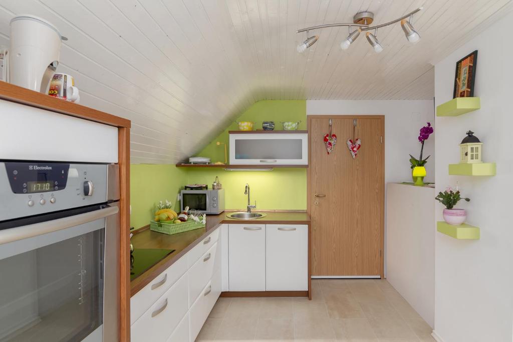 Elle comprend une petite cuisine avec des placards blancs et des murs verts. dans l'établissement Apartments Sara, à Bohinj