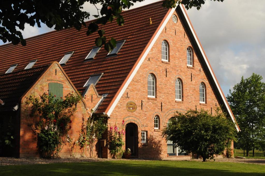 une grande église en briques rouges avec un toit brun dans l'établissement Der Deichhof - Ferienwohnungen, à Wremen