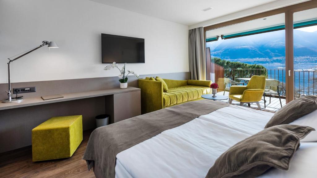 a bedroom with a bed and a tv and a balcony at Hotel Lago Maggiore - Welcome! in Locarno