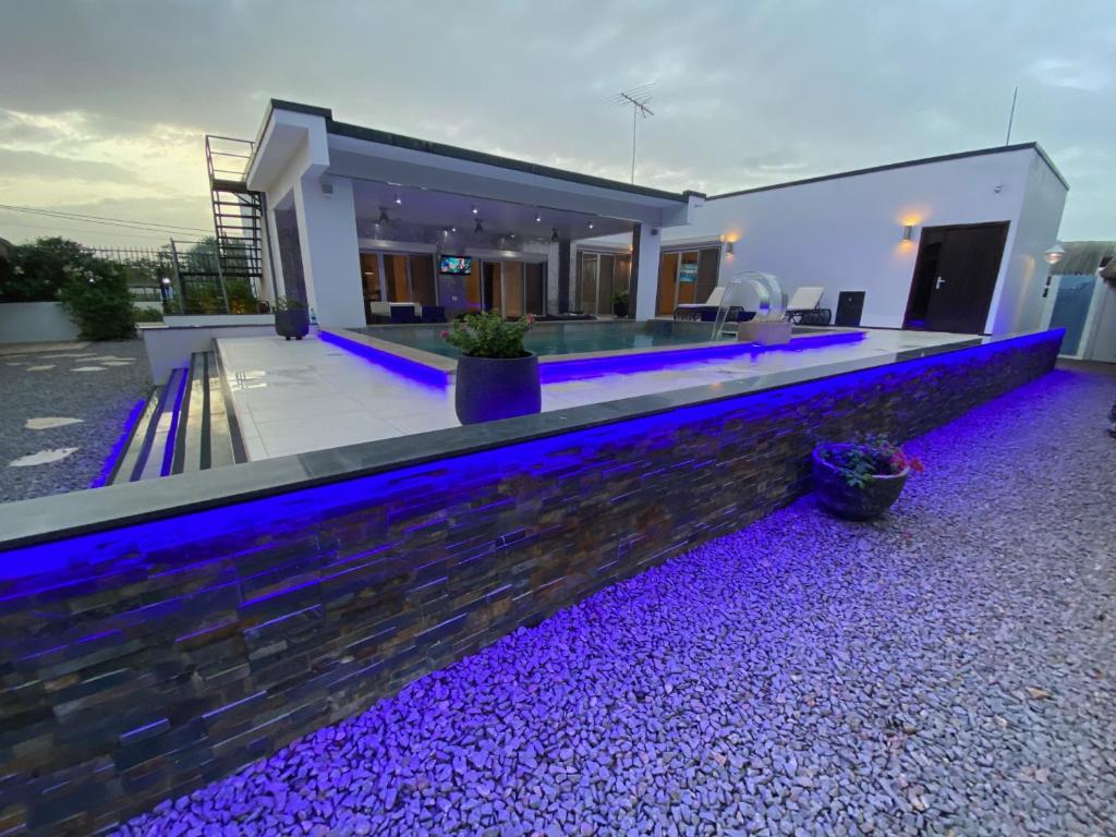 ein Haus mit einem Pool mit violetten Lichtern in der Unterkunft Liberdada Villa SURINAME in Wanica