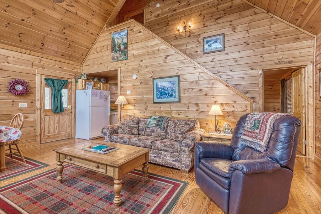 a living room with a couch and a table in a cabin at Cub Crossing, Free Attraction Tickets, Hot Tub, Pool Table, WIFI!!! in Sevierville