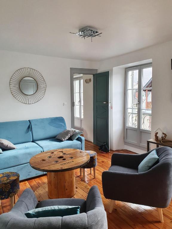 un salon avec un canapé bleu et une table dans l'établissement BEL APPARTEMENT LUCHON CENTRE WIFI - CLIMATISATION 6 COUCHAGES, à Luchon