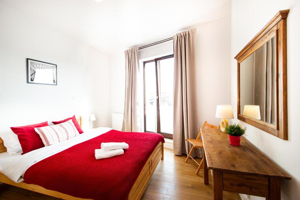 1 dormitorio con cama roja, mesa y ventana en Krasińskiego Żoliborz Stylish Apartment, en Varsovia