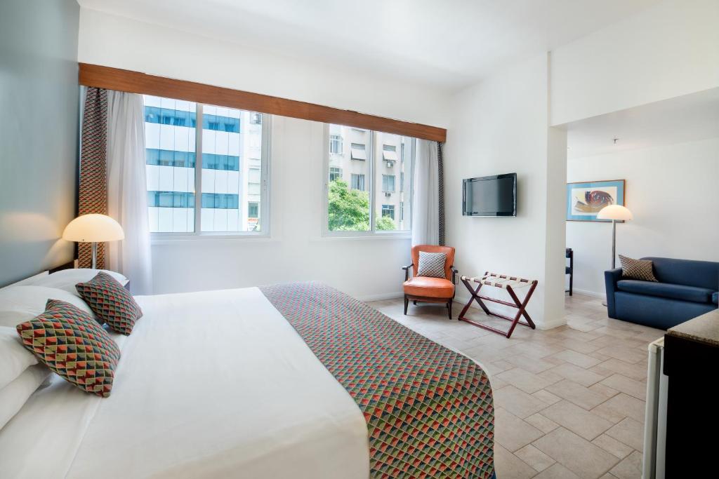 a bedroom with a large bed and a living room at Savoy Othon in Rio de Janeiro