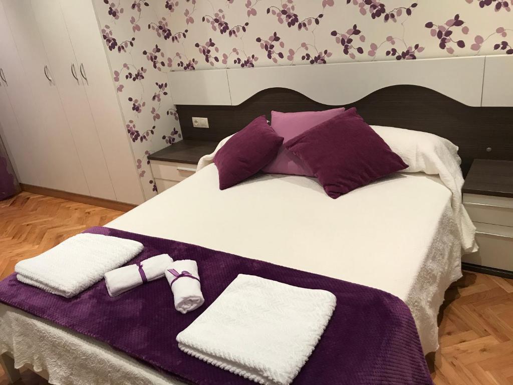 a large bed with purple and white towels on it at Apartamento turístico iguazu in Ribadeo