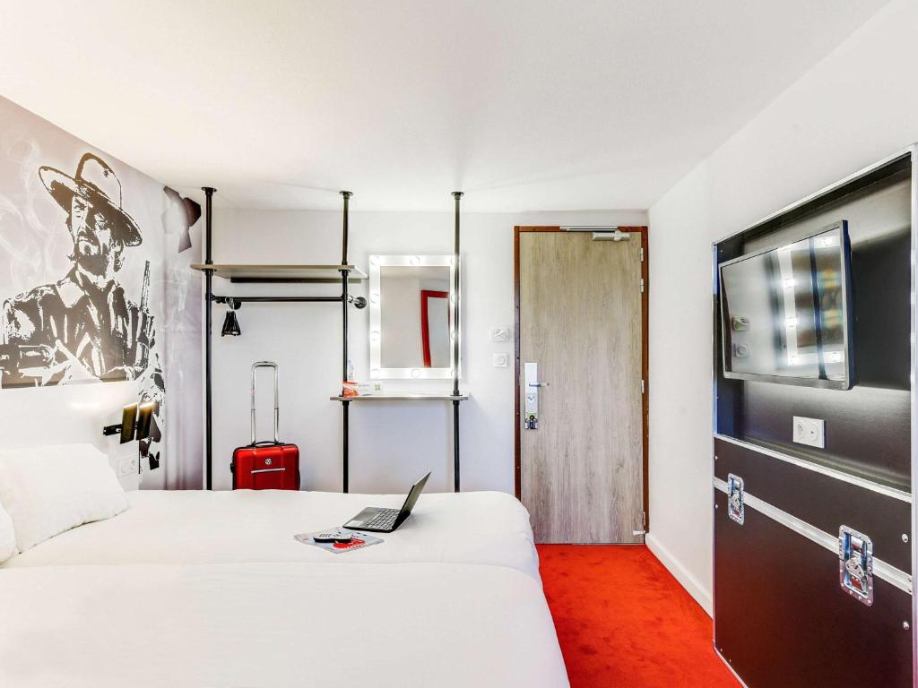 a hotel room with two beds and a laptop on the bed at Ibis Styles Paris Saint Denis La Plaine in Saint-Denis