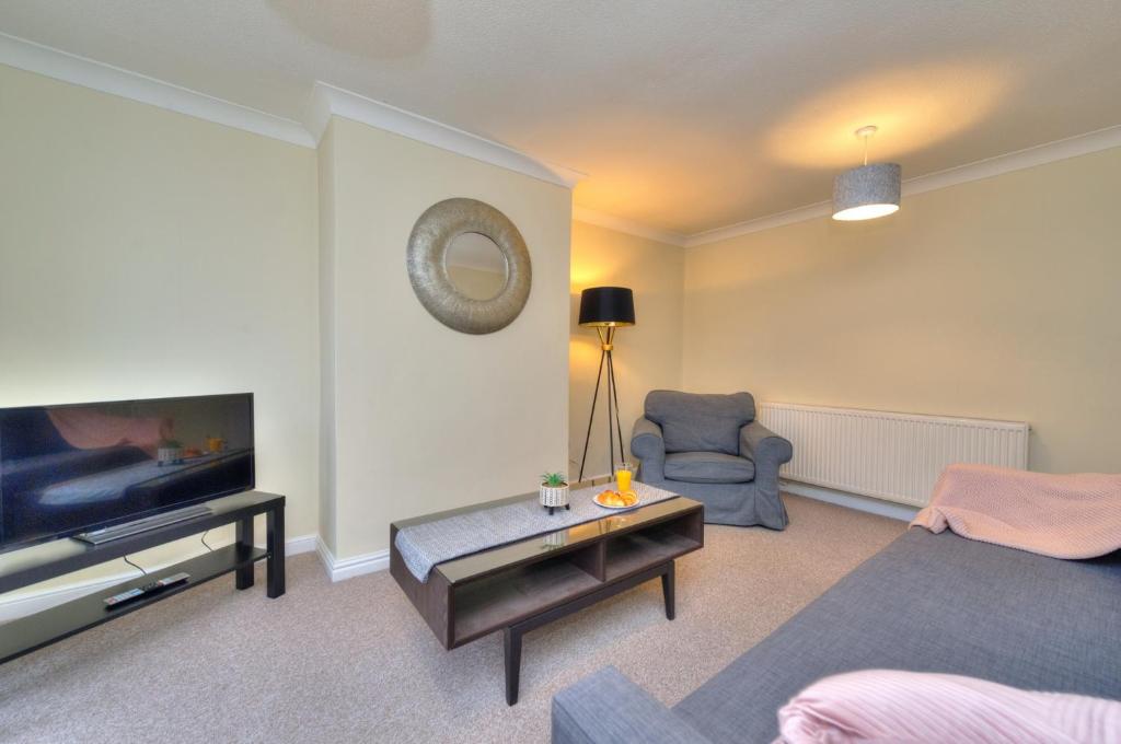 a living room with a television and a couch and a chair at Hampson House Stevenage by PAY AS U STAY in Stevenage