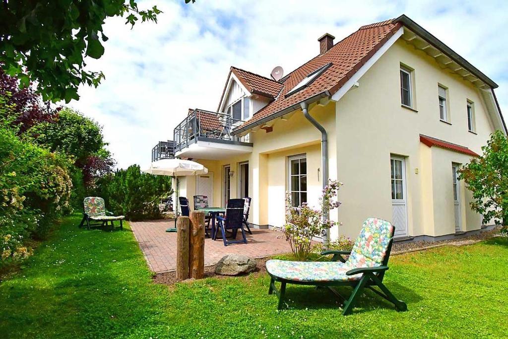 a house with chairs and an umbrella in the yard at Strandoase Typ STO-A STRANDOASE Whg. SO2 in Wustrow