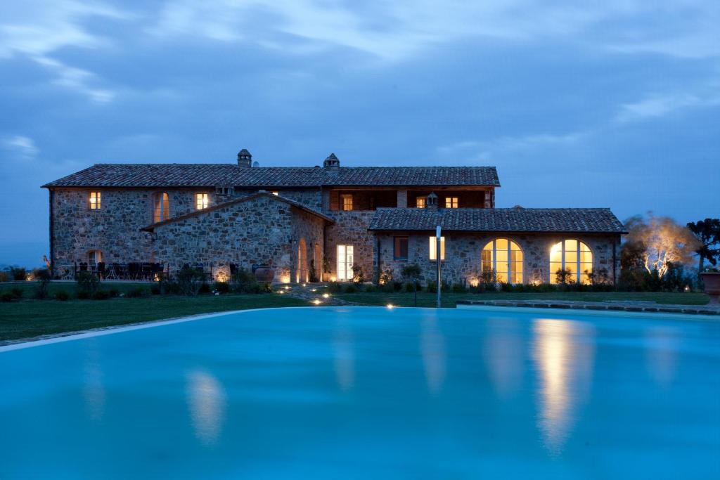 a large stone house with a swimming pool in front of it at Casanova di Neri Relais in Montalcino
