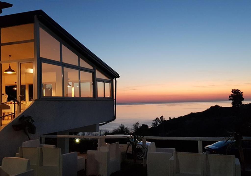 a house with a view of the ocean at sunset at HOTEL MERCURIO SUL MARE - Fish restaurant and private beach in Capo Vaticano