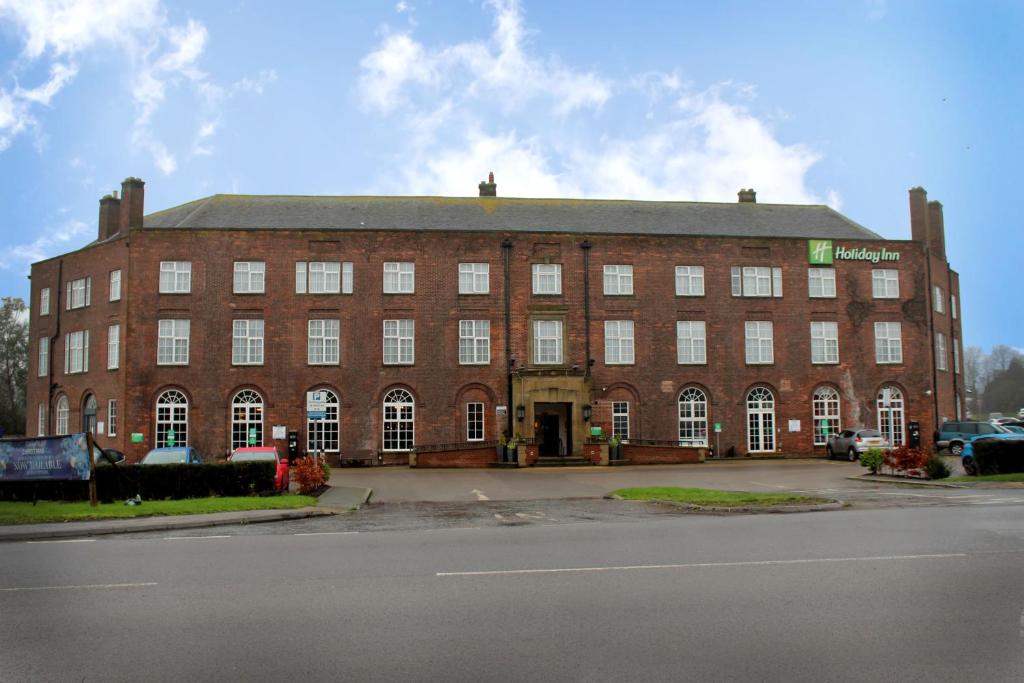 ein großes rotes Backsteingebäude mit weißen Fenstern in der Unterkunft Holiday Inn Darlington-A1 Scotch Corner, an IHG Hotel in Scotch Corner