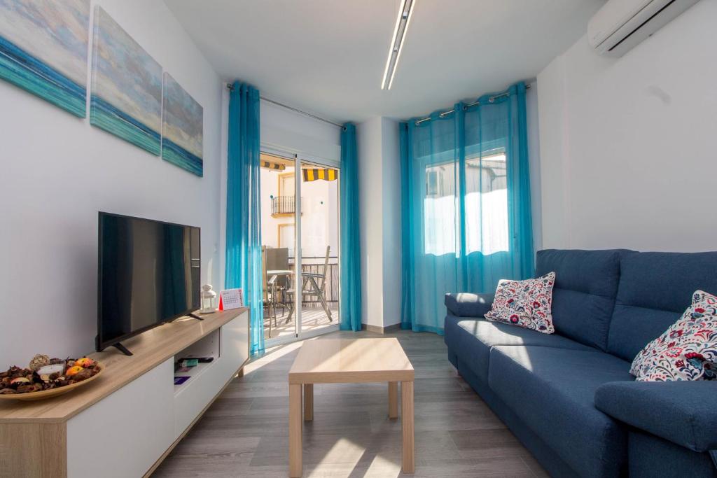 a living room with a blue couch and a tv at Santa Amalia 18 by IVI Real Estate in Torremolinos